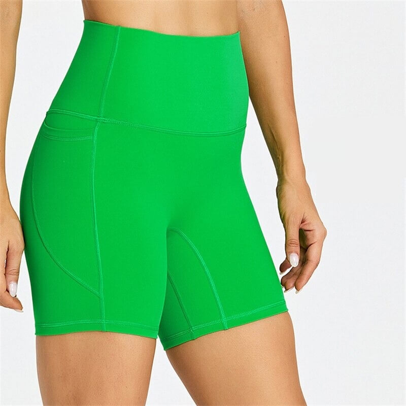 Women's green short tight solid-color workout shorts with pockets, perfect for mobility and comfort; nylon-spandex blend.